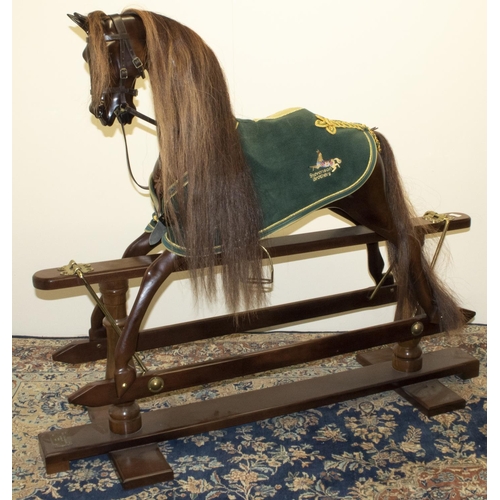 Stevenson Brothers - a chestnut coloured walnut rocking horse, with horse hair mane and tail, brass nailed leather saddle & tack and green rug, on swing base, with plaque for Stevenson Brothers England 5873 2004, L145cm H122cm