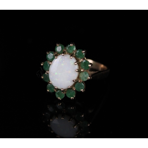 55 - 9ct gold opal and emerald cluster ring, the cabochon white opal surrounded by a halo of emeralds in ... 