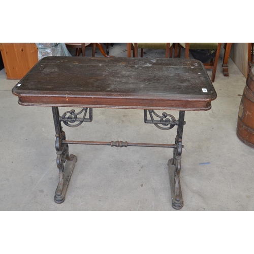 485 - Early C20th pub table, rectangular wooden top on pierced scrolled tapering cast iron end supports wi... 