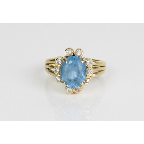 225 - 18ct yellow gold cluster ring, the central oval cut blue stone surrounded by brilliant cut diamonds,... 