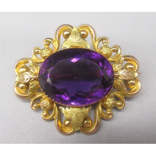 209 - 9ct yellow gold brooch set with large central oval cut amethyst, the border decorated with foliage d... 