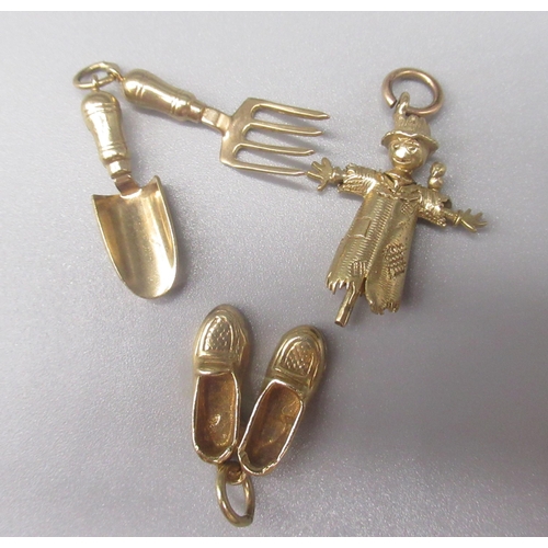 28 - Three 9ct yellow gold charms, including scarecrow, shoes and trowel and fork, all stamped 375, 7.9g