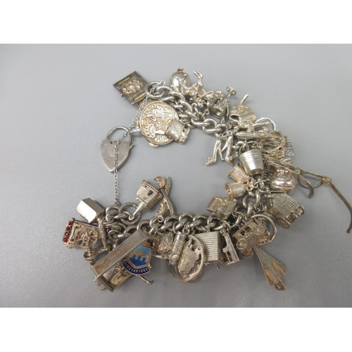 902 - Hallmarked Sterling silver charm bracelet with a quantity of silver and white metal charms, 137.3g, ... 