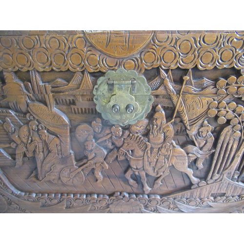 825 - Chinese camphor lined blanket box, deep carved with figures in landscapes, hinged lid with brass cla... 