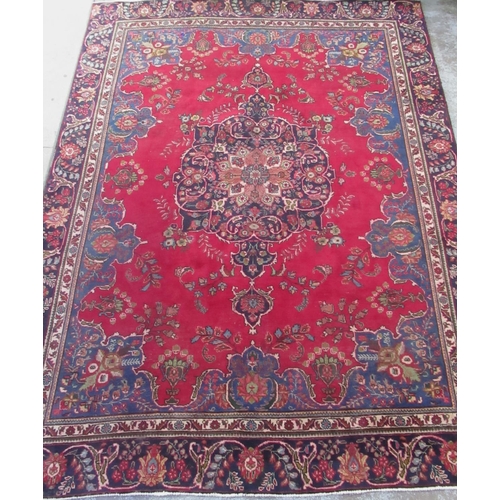 1440 - Large Persian pattern multicoloured wool rug, red field with central floral medallion and blue spand... 