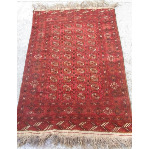 1442 - Bokhara red ground wool rug, field with octagonal medallions, in repeating hooked stylized striped b... 