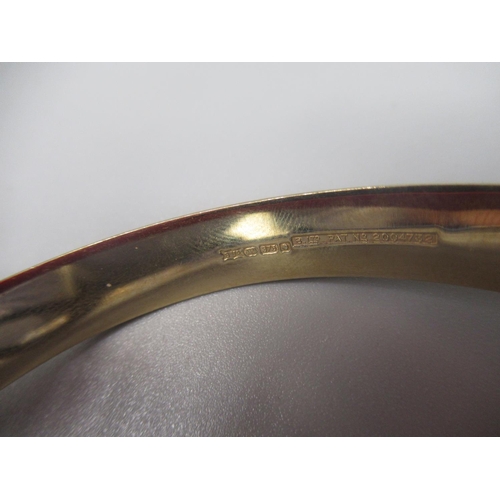 31 - 9ct yellow gold hinged bangle with engraved design and safety chain, stamped 375, 10.2g