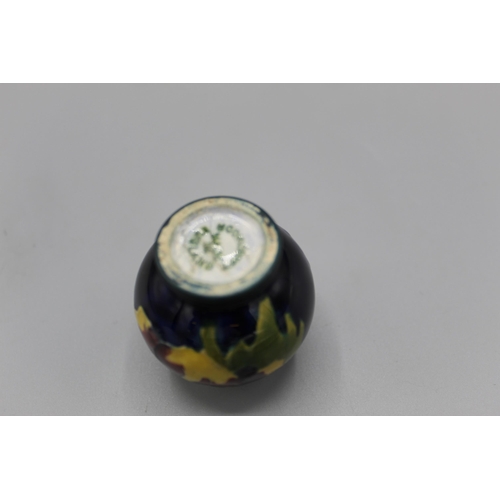 204 - Moorcroft Pottery: two Hibiscus pattern miniature vases, tube lined with purple and yellow flowers o... 