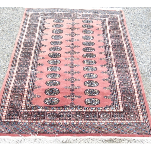 779 - Salmon ground Bokara pattern wall carpet, with elephants foot medallion field in repeating striped b... 