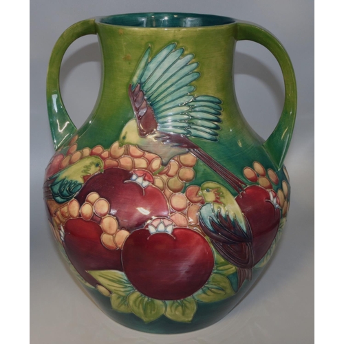 1141 - Moorcroft Pottery: Finches pattern twin handled vase, tubelined decoration of birds and fruit on a g... 