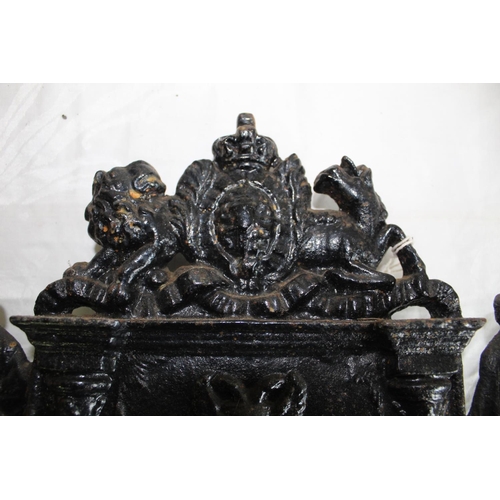 226 - Victorian black painted iron hearth ornament, cast as a fire place with two figures and Royal crest,... 