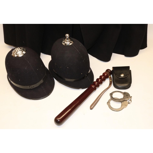 904 - Police uniform items comprising woollen cape, two helmets, truncheon, and a pair of handcuffs marked... 