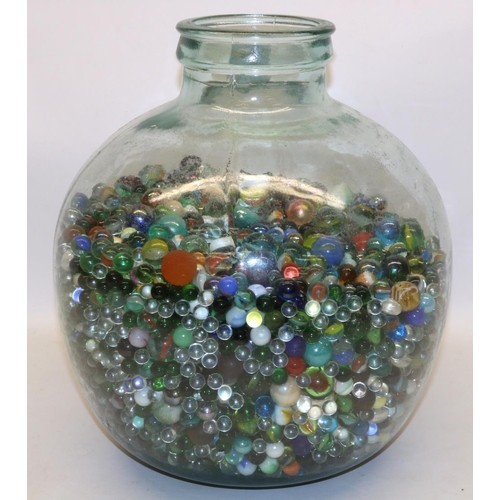 169 - Large collection of vintage and other glass marbles in a clear glass carboy