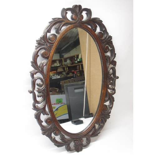 380 - C20th oval wall mirror in oak scroll carved pierced frame, H79cm W52cm