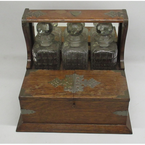 285 - Early C20th three decanter oak tantalus with plated mounts and games compartment W38cm