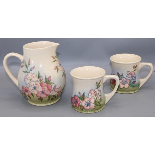 636 - Moorcroft Pottery: Spring Blossom pattern jug and two mugs, tube lined decoration of pink flowers on... 