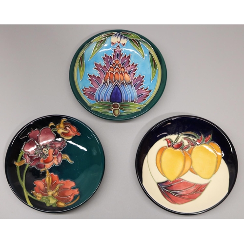 718 - Moorcroft Pottery: three pin dishes/coasters, purple and red flower design on dark green ground, des... 