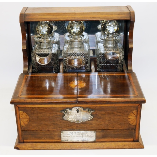 1139 - Edwardian Sheraton Revival satinwood banded oak presentation tantalus, three square decanters with s... 