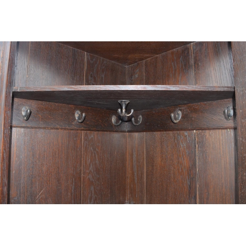 211 - C20th oak arts and crafts style hall corner wardrobe with carved floral motifs, open shelf above pan... 