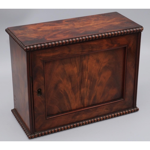 1152 - Early C19th figured mahogany table top key cupboard, with panel door and bead mouldings, interior wi... 