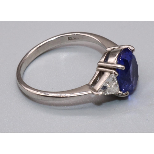1002 - Platinum three stone tanzanite and diamond ring, the central oval cut tanzanite flanked by two trian... 