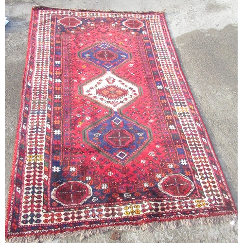 1313 - Multicoloured Shiraz rug, triple hooked medallion in red ground field with elephant foot spandrels i... 