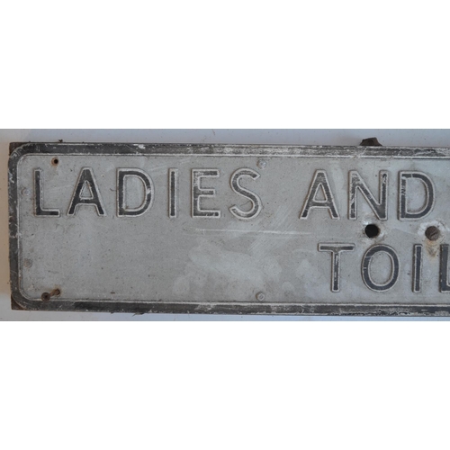 291 - Vintage relief text pressed metal Ladies And Gentlemen's Toilets sign on steel frame, 104x18cm