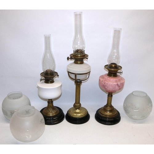 198 - Three C19th century brass column oil lamps with black bases, incl. one with marbled pink glass reser... 