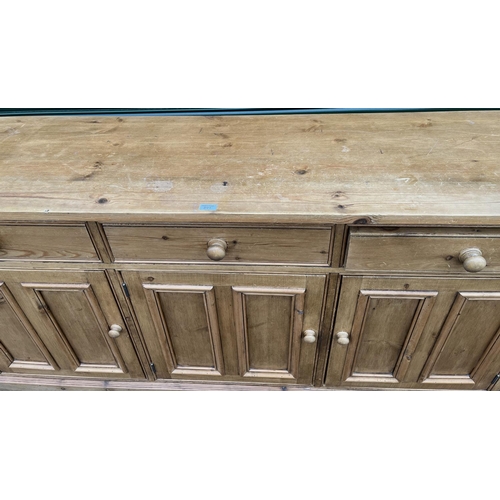 591 - Waxed pine dresser base with three drawers above three twin panel doors with turned wooden handles o... 