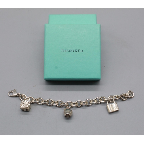 238 - Tiffany & Co Silver chain charm bracelet with three tiffany & Co silver charms of a padlock, present... 