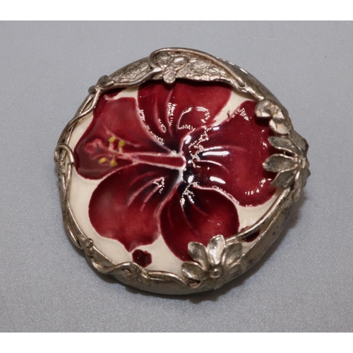 Moorcroft Pottery: ‘Hibiscus’ pattern ceramic roundel set in a silver foliate mount, mount stamped MRB, London 1989, D3.5cm