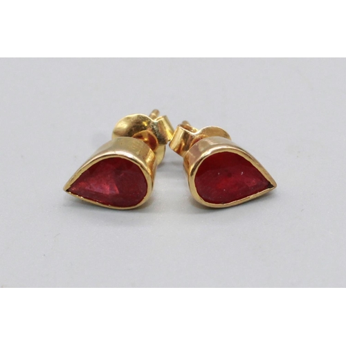39 - Pair of yellow metal ruby earrings, the teardrop cut rubies in rub over settings, one back stamped 9... 