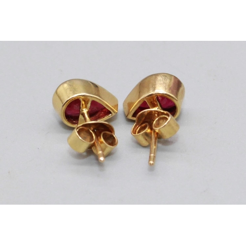 39 - Pair of yellow metal ruby earrings, the teardrop cut rubies in rub over settings, one back stamped 9... 