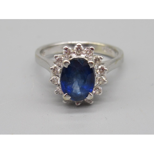 67 - 18ct white gold sapphire and diamond cluster ring, the central oval cut sapphire surrounded by a hal... 