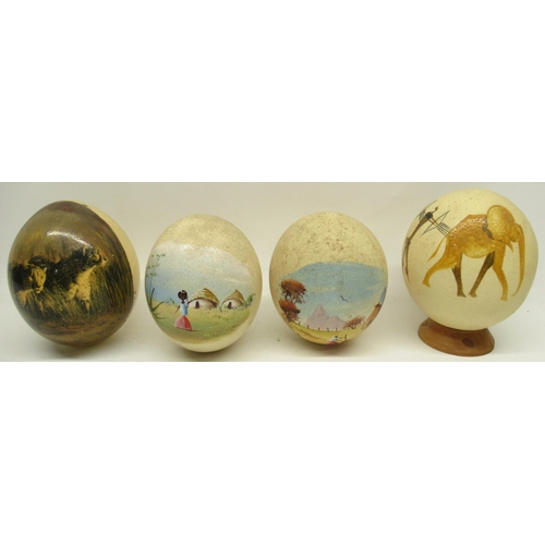 1123 - Four decorated ostrich eggs, one on turned wooden stand, 16cm