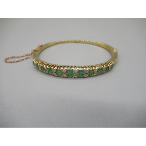 1001 - 15ct yellow gold hinged bangle set with graduated emeralds cut emeralds and brilliant cut diamonds, ... 