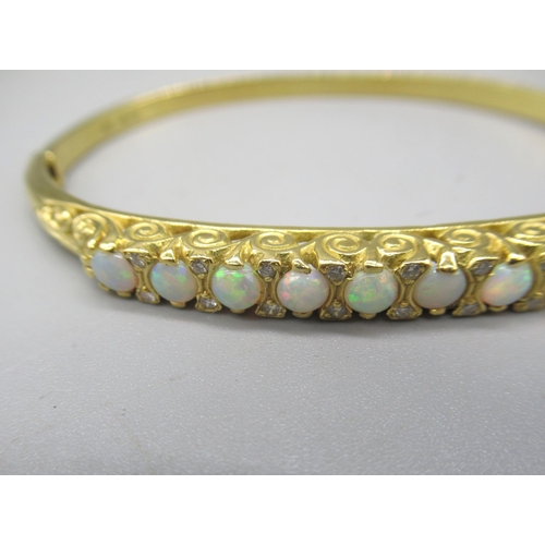 1013 - 18ct yellow bangle set with nine opals between brilliant cut diamonds on scroll mount, stamped 750, ... 