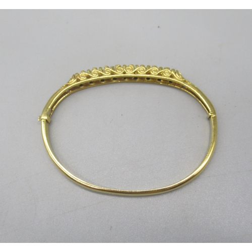 1013 - 18ct yellow bangle set with nine opals between brilliant cut diamonds on scroll mount, stamped 750, ... 