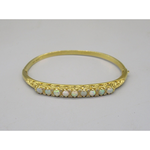 1013 - 18ct yellow bangle set with nine opals between brilliant cut diamonds on scroll mount, stamped 750, ... 