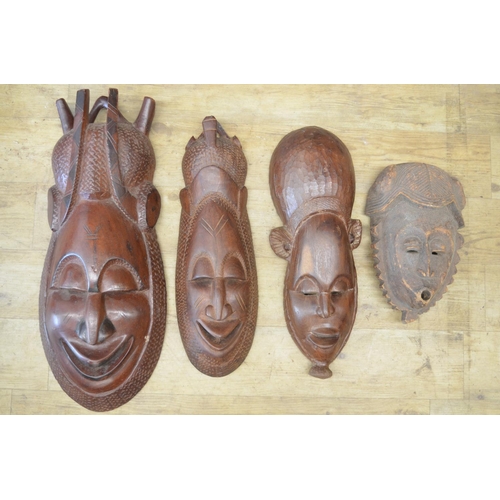 92 - A selection of four carved wooden masks of various styles and time-periods, most likely originating ... 