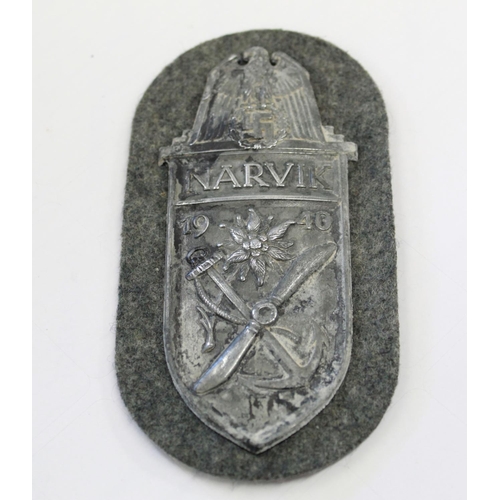 246 - WWII German Narvik Shield with cloth backing. backing paper and four prongs intact