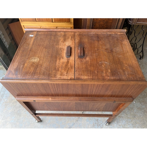 603 - Mid 20th century teak drinks trolley, hinged top revealing internal shelf and five bottle compartmen... 