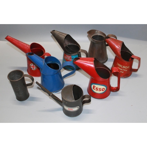 318 - Set of eight oil pouring cans. Including Esso, Bluecol anti freeze, and Thelson Tractor oil