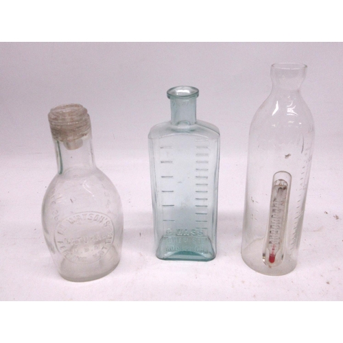 241A - Three clear glass antique feeding bottles, one with thermometer, and a C. Wass Chemist clear glass b... 