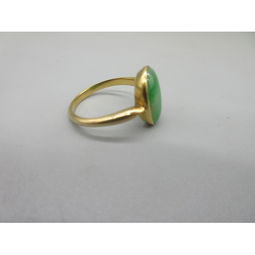 1016 - Yellow metal jade ring, the oval cut cabochon jade in rub over mount, unmarked, size N, 3.77g