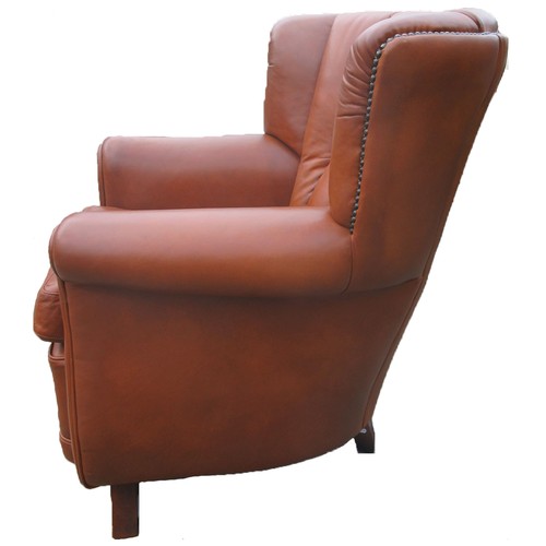 1320 - Brown leather upholstered arm chair, pleated bow back, and scroll arms with loose seat cushion on an... 