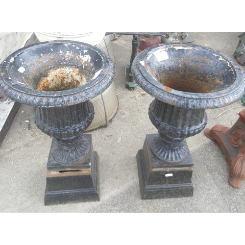 1323 - Small pair of cast iron urns on plinths. Height 50cm. Pair of cast iron ornate tee-light / candle st... 