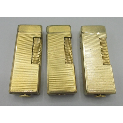 173 - Dunhill Patented gold plated butane cigarette lighter, engine turned decoration and two similar ligh... 