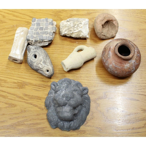 1043 - Selection of roman artifacts, including ceramic lion head, ornate oil lamp, small clay jug etc.