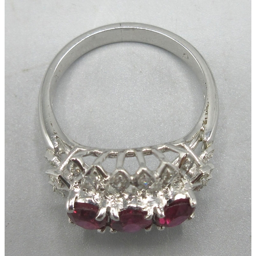 165 - White metal ring set with three rubies surrounded by diamonds, unmarked, size M, 4.27g